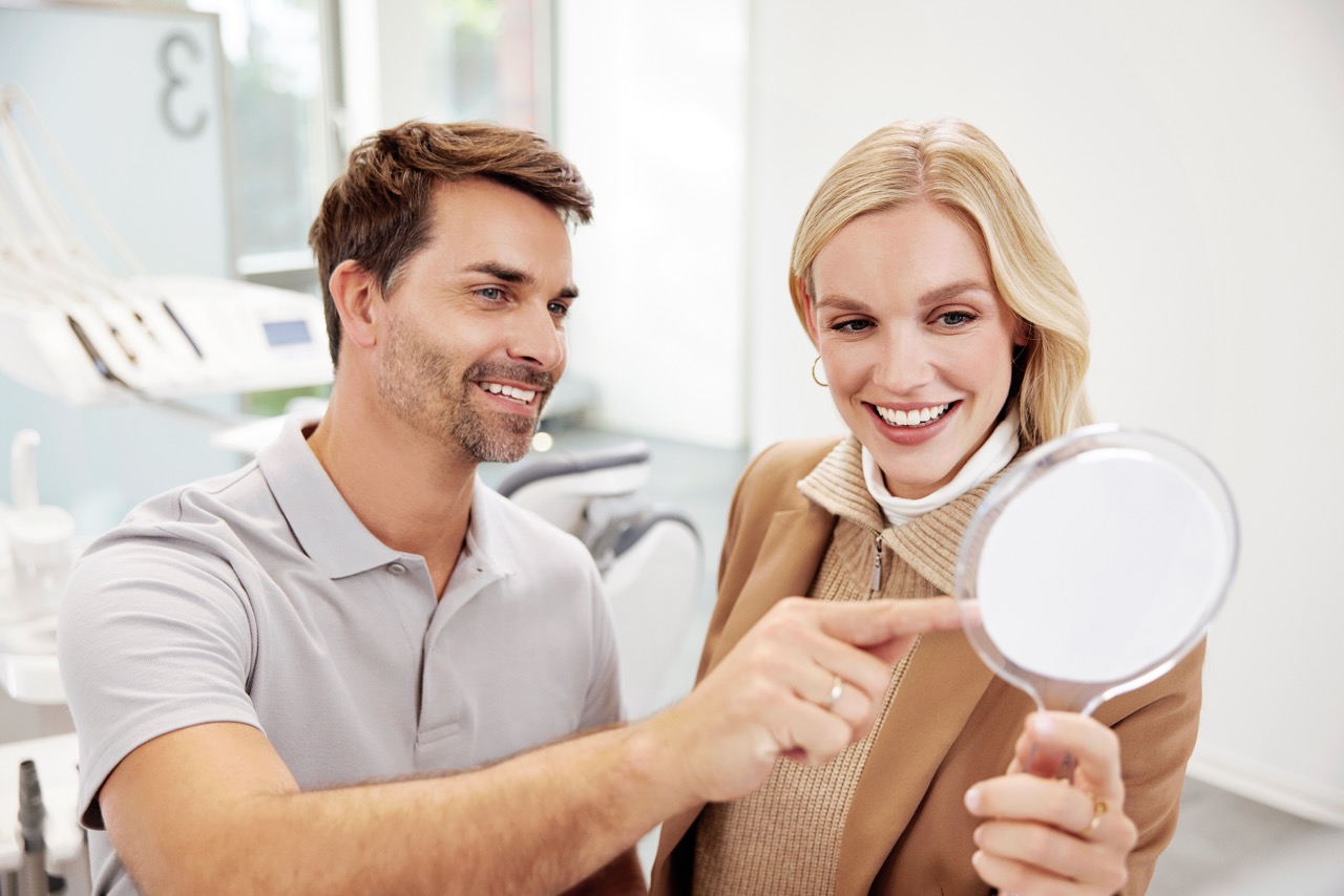 A patient reviewing their Spark™ treatment outcome in a handheld mirror — Spark brand photography