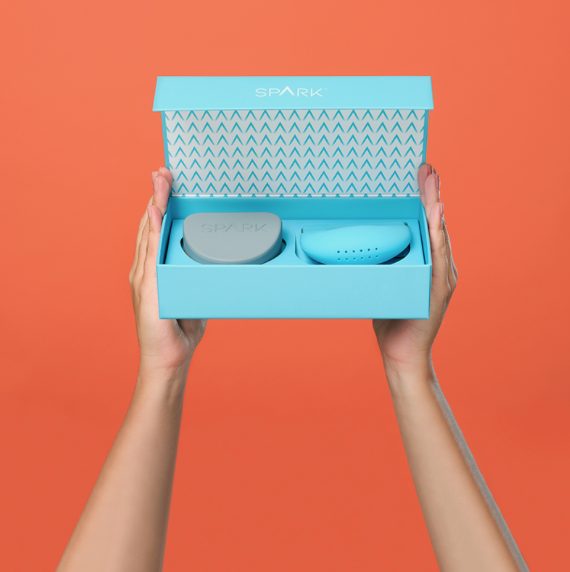 Spark™ retainer case with aligner storage tray held against a coral background