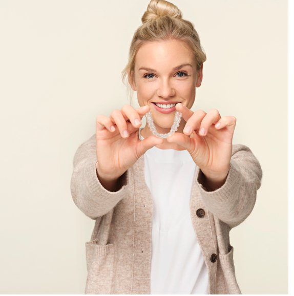 Spark™ clear aligner tray held up in front of a smile — product showcase